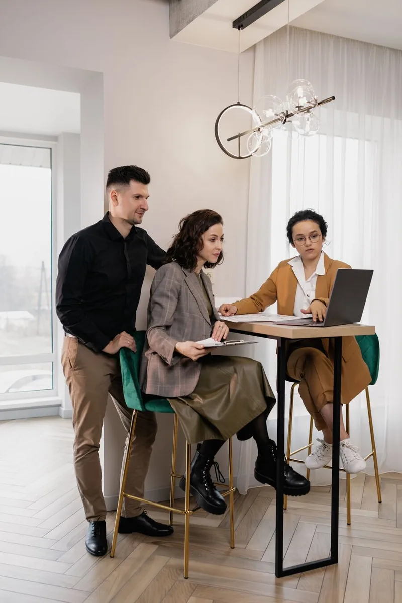 Three colleagues reviewing work on a laptop